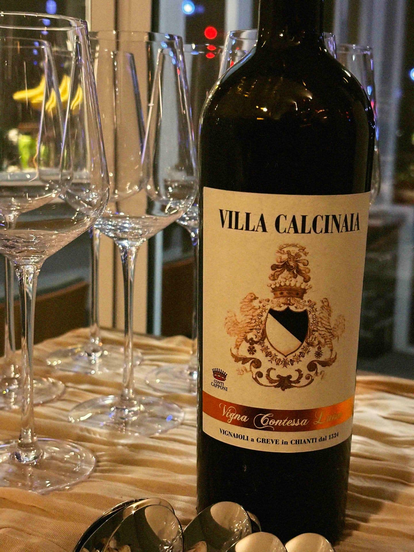 A bottle of Villa Calcinaia wine beside empty glasses at a Luma Society dinner